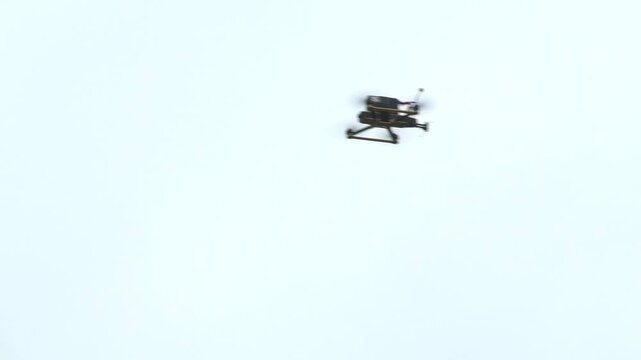 FPV drone flying and hovering in the sky while searching for a target. Concept of modern warfare, aerial surveillance, and attack drones in combat conditions. Military technology, unmanned systems