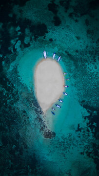 Aerial view of Naked Island sandbar surrounded by turquoise waters and coral reefs with outrigger boats moored on the shore Nake