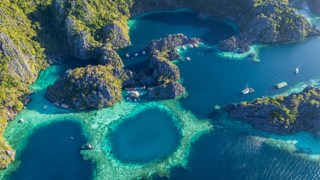 Aerial top-down drone view of the iconic Barracuda Lake in Coron, Palawan. A circular turquoise lagoon hidden within massive limestone karst formations in the Philippines