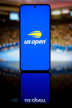 US Open tennis logo displayed on a smartphone screen with a blurred stadium background, representing mobile sports broadcasting and grand slam tournament app coverage