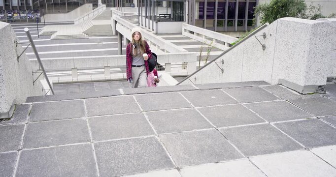 Diverse female friends climbing stairs, lead reaching top and calling to coordinate crossing plaza