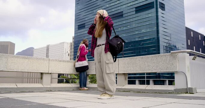 Diverse women terrace beanie fiddling, fixing headset, scrolling phone, walking past rail caller