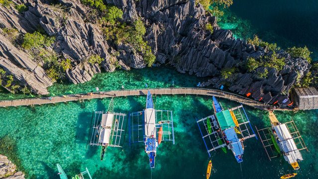 Aerial drone view of traditional bangka boats at Twin Lagoon in Coron, Palawan. Stunning turquoise water surrounded by iconic limestone karst cliffs in the Philippines