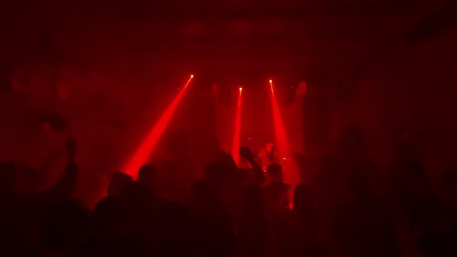 Crowd of Unrecognizable People Dancing at Underground Techno Rave Party with Bright Red Laser Beams and White Spotlights in Dark Smoky Nightclub Interior Intense Electronic Music Event Atmosphere