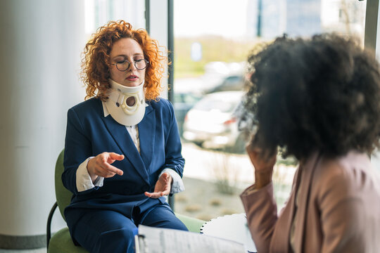 Woman with neck brace discussing legal compensation with lawyer