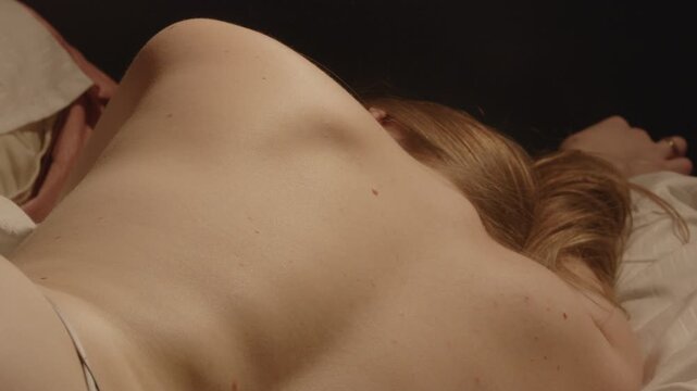 Close up of the bare back of a beautiful topless woman lying in bed