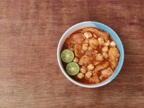 Indonesian street food spicy seblak in a bowl on wooden table background. Perfect for culinary, food, or Asian cuisine themes