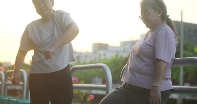 Two happy Asian senior women warm up before morning exercise at the park.