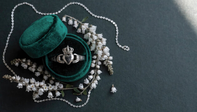 A traditional sterling silver claddagh ring resting inside a luxurious emerald green velvet box illustration