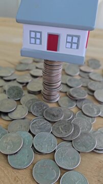 Building wealth with coins and a miniature house on a stack of quarters in a simple setup