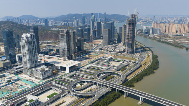Aerial view of modern skyscrapers piercing the skyline above a complex network of roads and bridges alongside the shimmering river, Zhoushan, China.