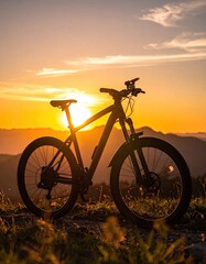 Fototapeta premium A silhouette of a mountain bike rests on a grassy slope against a vibrant sunset.