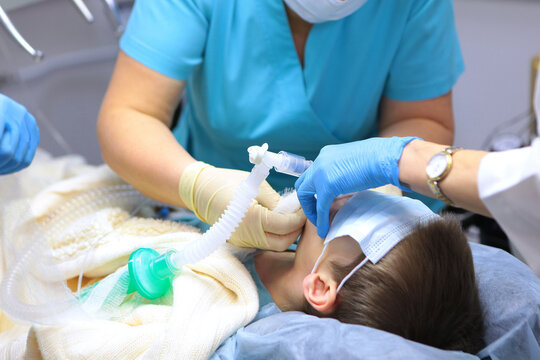 The little boy is under general anesthesia. Treatment of baby teeth under anesthesia. A breathing tube in the baby's mouth. Surgical intervention.