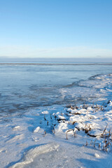Naklejka premium Landscape, blue sky and lake with snow in nature for climate change, winter season and morning frost. Space, meadow and river with ice formation, frozen field and icy conditions from global warning