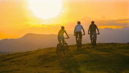 Fototapeta premium SUN FLARE Young cross country cyclists enjoying a relaxing ride on sunny evening