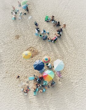 Aerial view of sunbathers and colorful umbrellas dotting the sandy expanse of the beach, creating a vibrant tapestry of summer leisure, Vejer de la Frontera, Andalusia, Spain.