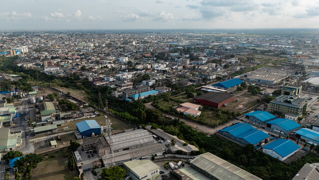 Aerial view of industrial buildings and residential areas intermingle under a vast sky, creating a textured urban mosaic, Ogba, Lagos, Nigeria.