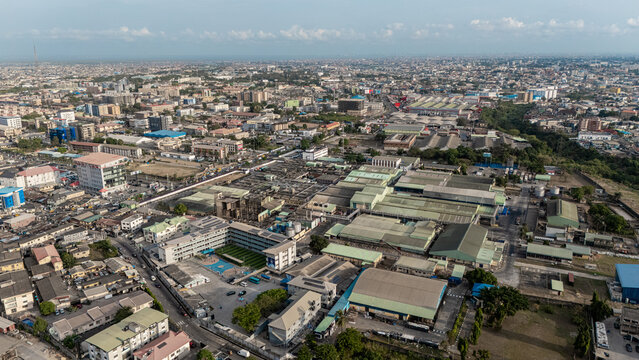 Aerial view of sprawling industrial complexes and urban landscape converge under a vast sky, creating a tapestry of human activity, Ogba, Lagos, Nigeria.