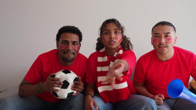 Diverse group of young soccer fans watching a match on television at home. They experience a rollercoaster of emotions, from tension to celebration
