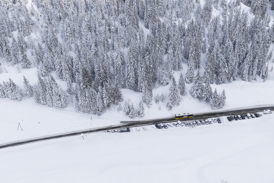 Aerial view of a winding road cutting through a snow-laden landscape, the pine trees heavy with snow, Col du Pillon, Ormont-Dessus, Vaud, Switzerland.