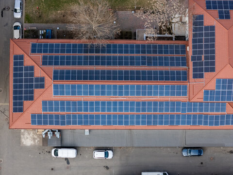 Aerial view of a building roof adorned with neat rows of dark solar panels contrasting against the warm terracotta tiles, Bucharest, Bucharest, Romania.