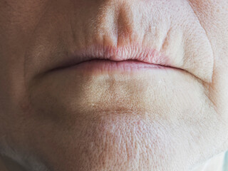 Naklejka premium Mature woman shows details of aging skin with wrinkles and texture on the face in a close-up view