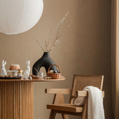 Naklejka na ściany i meble A refined Easter breakfast setup featuring a wooden dining table, a rattan chair, and a black sculptural vase with soft willow branches, creating a sophisticated seasonal atmosphere.