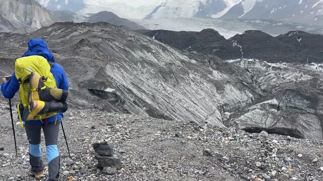Group of Climbers in mountaineering Gear, backpacks and trekking poles during Lenin peak glacier crossing with mountain peaks in background. Extreme active people, high-altitude mountaineering concept