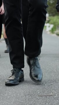 Legs, people and walking at cemetery for funeral procession, mourning and loss at ceremony. Feet, shoes and group for steps on ground, outdoor or grief at graveyard with farewell, support and death