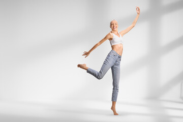 Tall slim woman in jeans and white crop top dancing