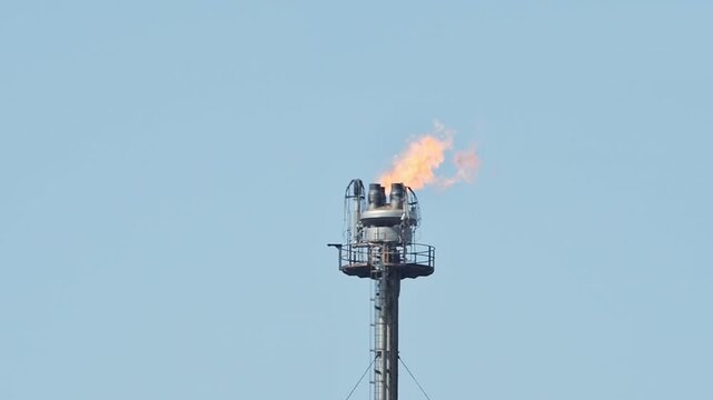 Tower with a smokestack, flame at the top. flare unit. Combustion of exhaust gases at an oil refinery. Metal structure. pollution, CO2 emissions War Iran, Kuwait, Strait of Hormuz, Kharg Island