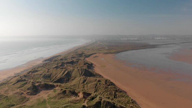 Drone glides smoothly over rugged coastal cliffs and sandy beaches at Tramore, revealing vast untouched beauty and inspiring deep awe and serenity.
