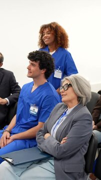 Multiethnic group of doctors, nurses, and hospital staff sitting in an audience and listening attentively during a medical conference, professional development seminar, or educational lecture