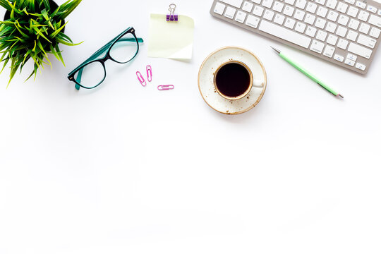 Home office workspace with computer keyboard and cup of coffee on white background, top view. Education online. Tabletop of freelancer.
