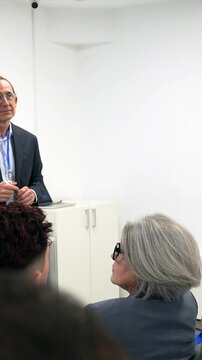 Professional male doctor in a suit giving a presentation to a diverse group of medical students and interns during a healthcare seminar in a modern hospital conference room