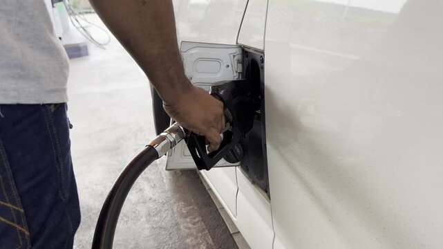 A close-up shot of a man refueling a van himself. The text on the fuel cap in Thai translates to "diesel".