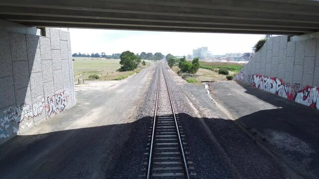 Aerial View Flying Along Railway Tracks Under Bridge