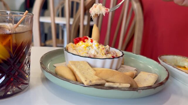 Close-up view of the hand of a caucasian man eating handmade ensaladilla rusa salad with a fork in a traditional spanish bar.