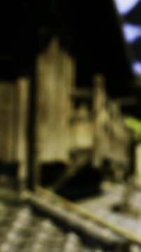 Workers are present at a construction site where a wooden structure is being built. The sun sets, casting shadows on materials and tools scattered around.