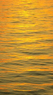 Water sunset reflection shimmering across the ocean surface creating a peaceful golden background texture during twilight.