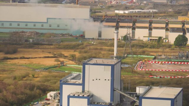 Industrial biomass energy facility converting recycled wood waste. Sustainable infrastructure and green energy production at a modern power station in UK. Timelapse clip.