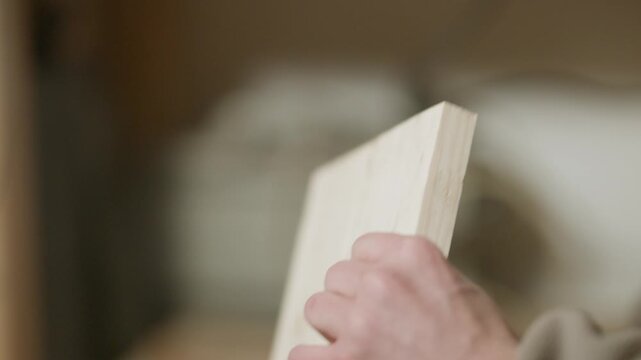 A skilled woodworker meticulously uses a clamp to secure a piece of wood during a project. The hands of a craftsman carefully adjust the tool on the timber.