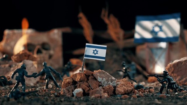 Conceptual diorama of a battlefield with plastic toy soldiers fighting. The israeli flag is planted on a pile of rocks amidst smoke and explosions