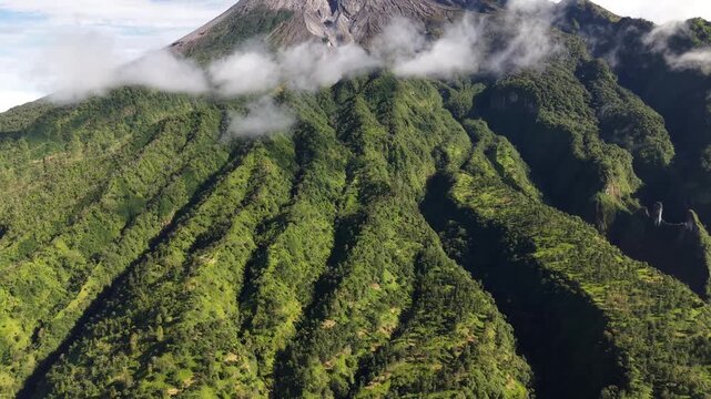 4K cinematic aerial footage of Mount Merapi in Yogyakarta, showing the valley and peaks. The weather is clear with blue skies.