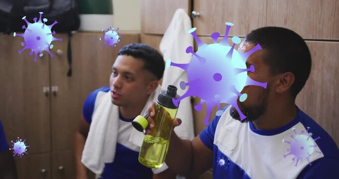 Animation of covid-19 cells icons over hispanic male soccer player putting water on his face