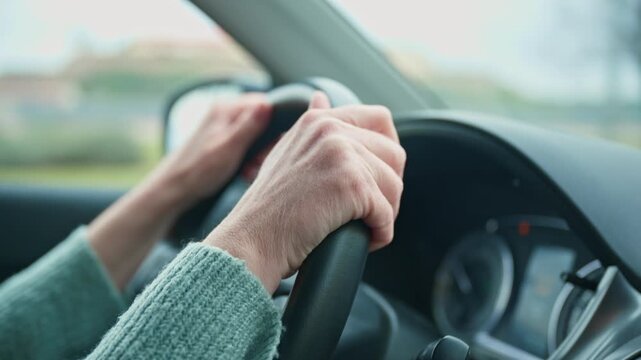Close-up of woman&rsquo;s hands gripping steering wheel while driving, focus on control and road safety, 4K with selective focus