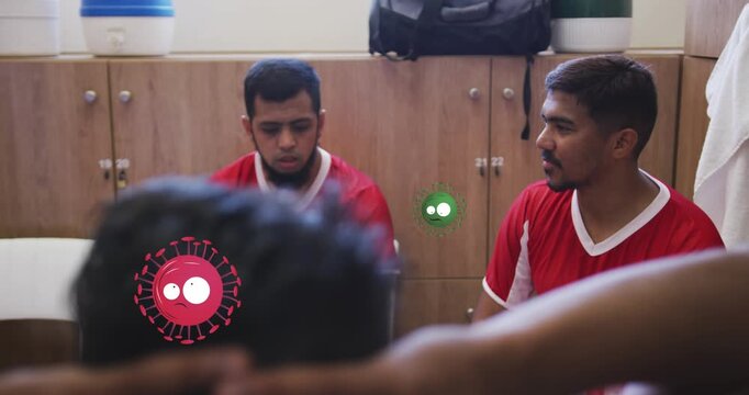 Animation of covid-19 cells icons over team of diverse male soccer players discussing in locker room