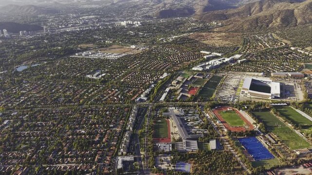 High-altitude drone panorama rotating over the university and surrounding valley, San Carlos de Apoquindo, Las Condes, Chile, 4K.