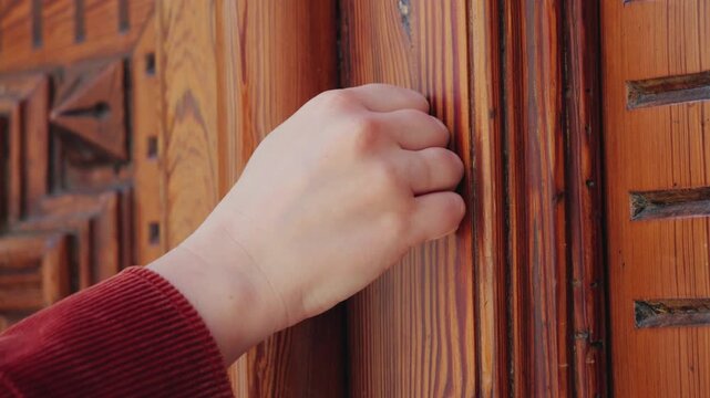 Close-up of a hand knocking on a wooden door. Entrance, arrival, communication and request concept. High quality 4k footage