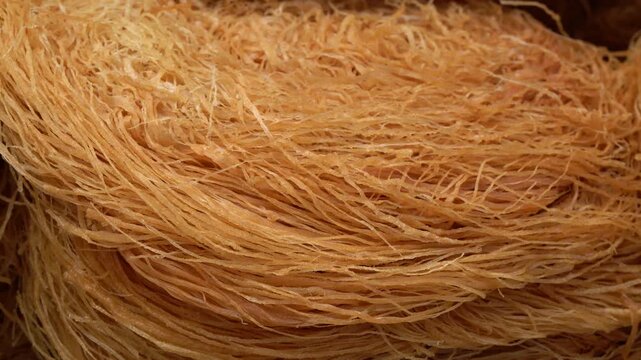 Raw kataifi dough for kunafa rotating, showing the thin noodle pastry texture. Close-up of this traditional shredded phyllo dough, a key ingredient for middle eastern desserts